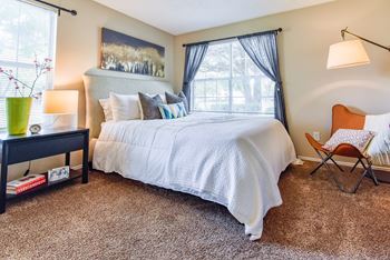 a bedroom with a large bed and a chair next to a window  at Riverset Apartments, Tennessee